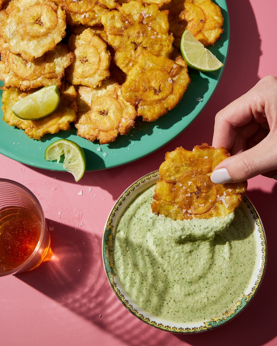 dipping friend tostones in green sauce