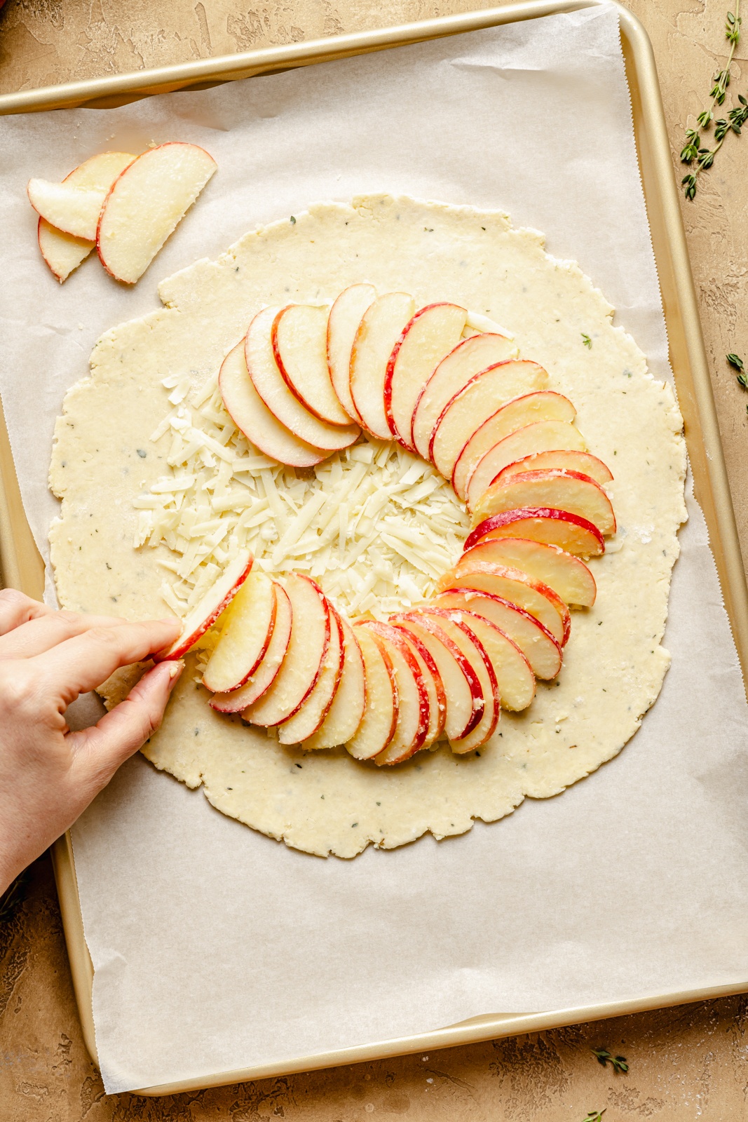 laying apples on pie dough to make an apple cheese galette