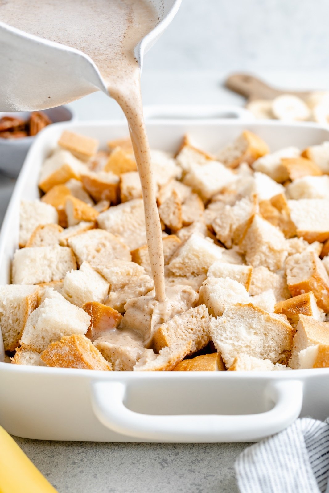 pouring an egg mixture into a pan with banana french toast casserole