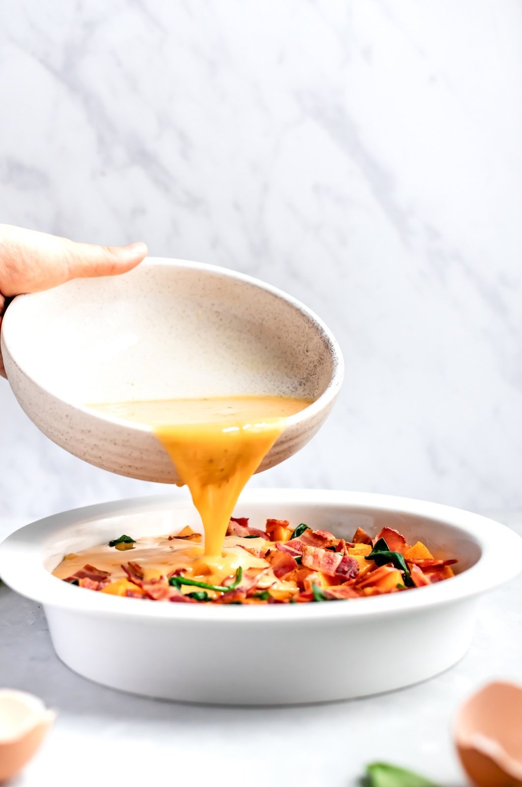 eggs being poured into pie pan for butternut squash quiche