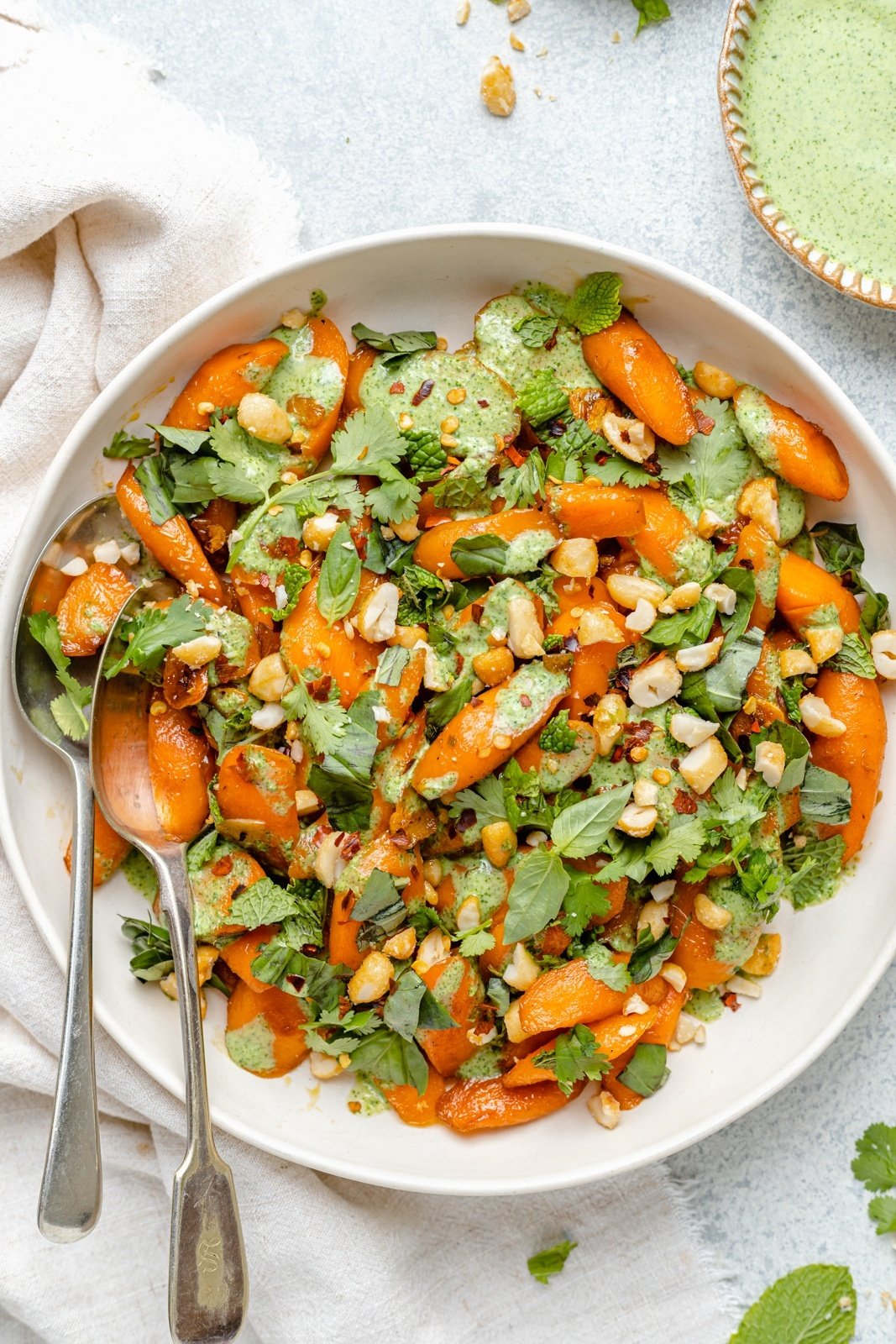 caramelized carrots in a bowl with fresh herbs and jalapeño cilantro yogurt sauce