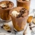 three chocolate peanut butter banana smoothies in glasses