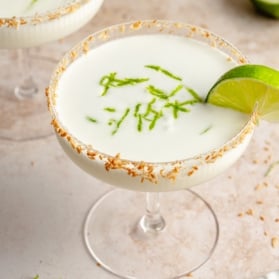 coconut margarita in a glass with a lime wedge