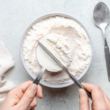 measuring flour with a measuring cup and knife