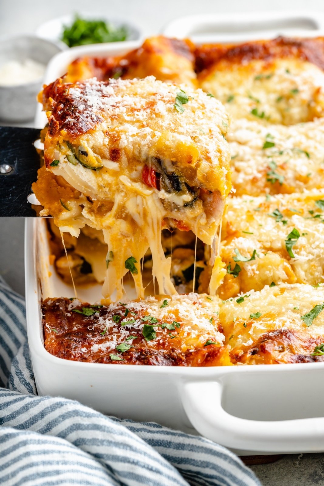 lifting a slice of butternut squash lasagna out of a pan