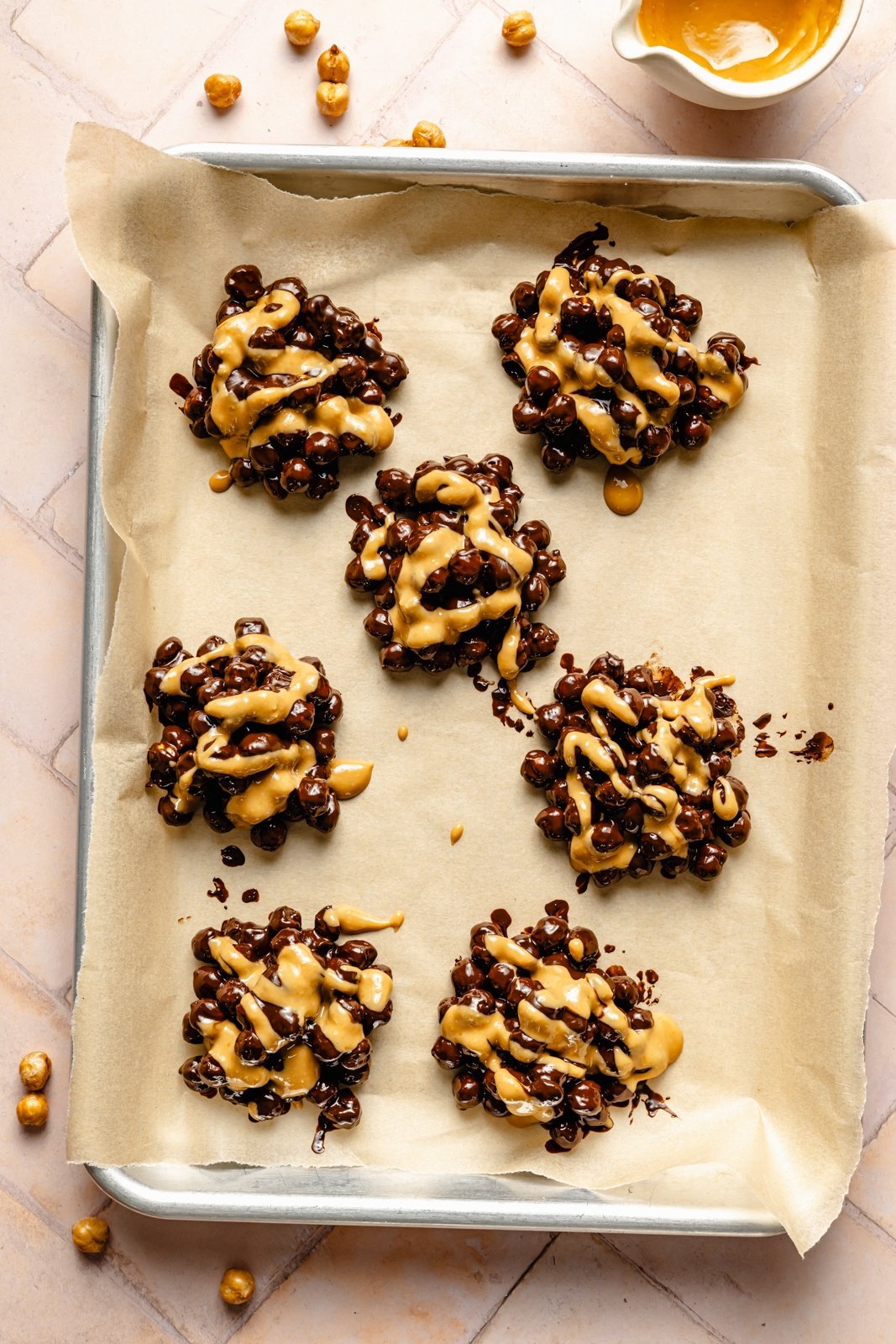 chocolate chickpea clusters drizzled with peanut butter on a baking sheet