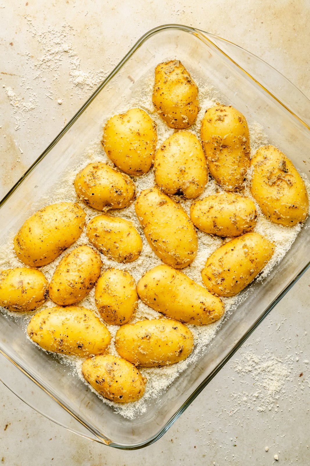 parmesan potatoes in a glass pan before roasting