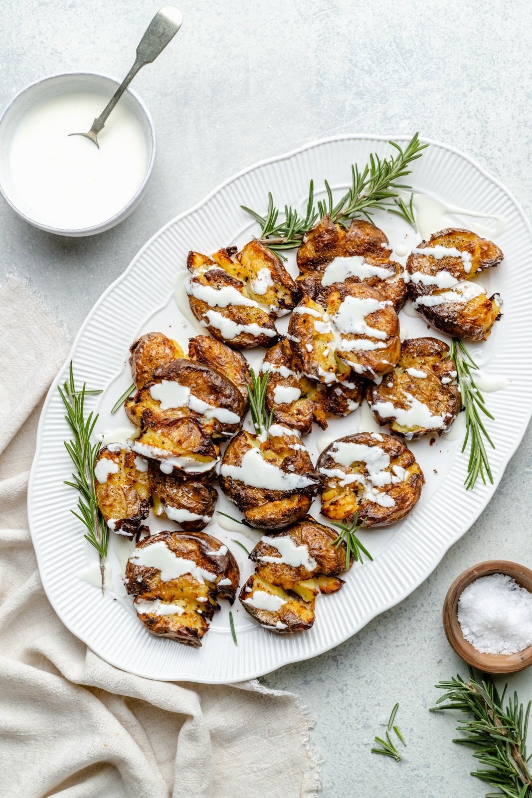 healthy smashed potatoes drizzled with sauce on a platter