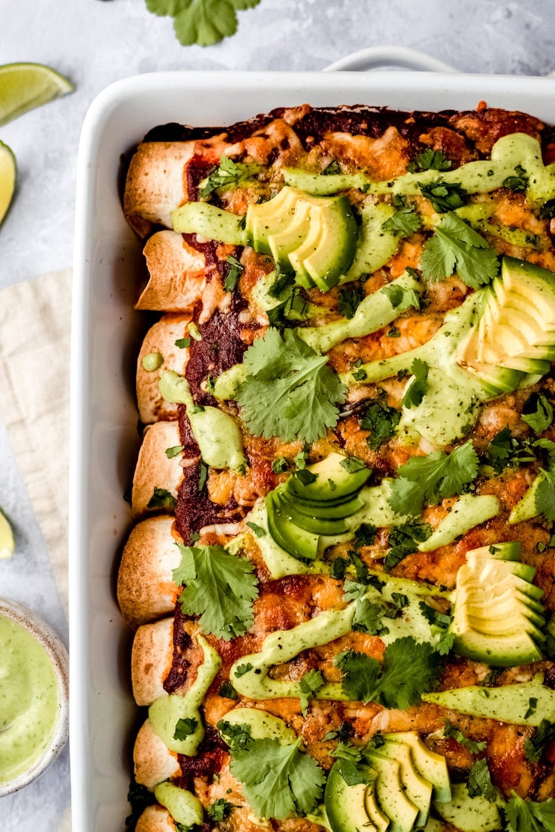 vegetarian enchiladas in a pan topped with avocado