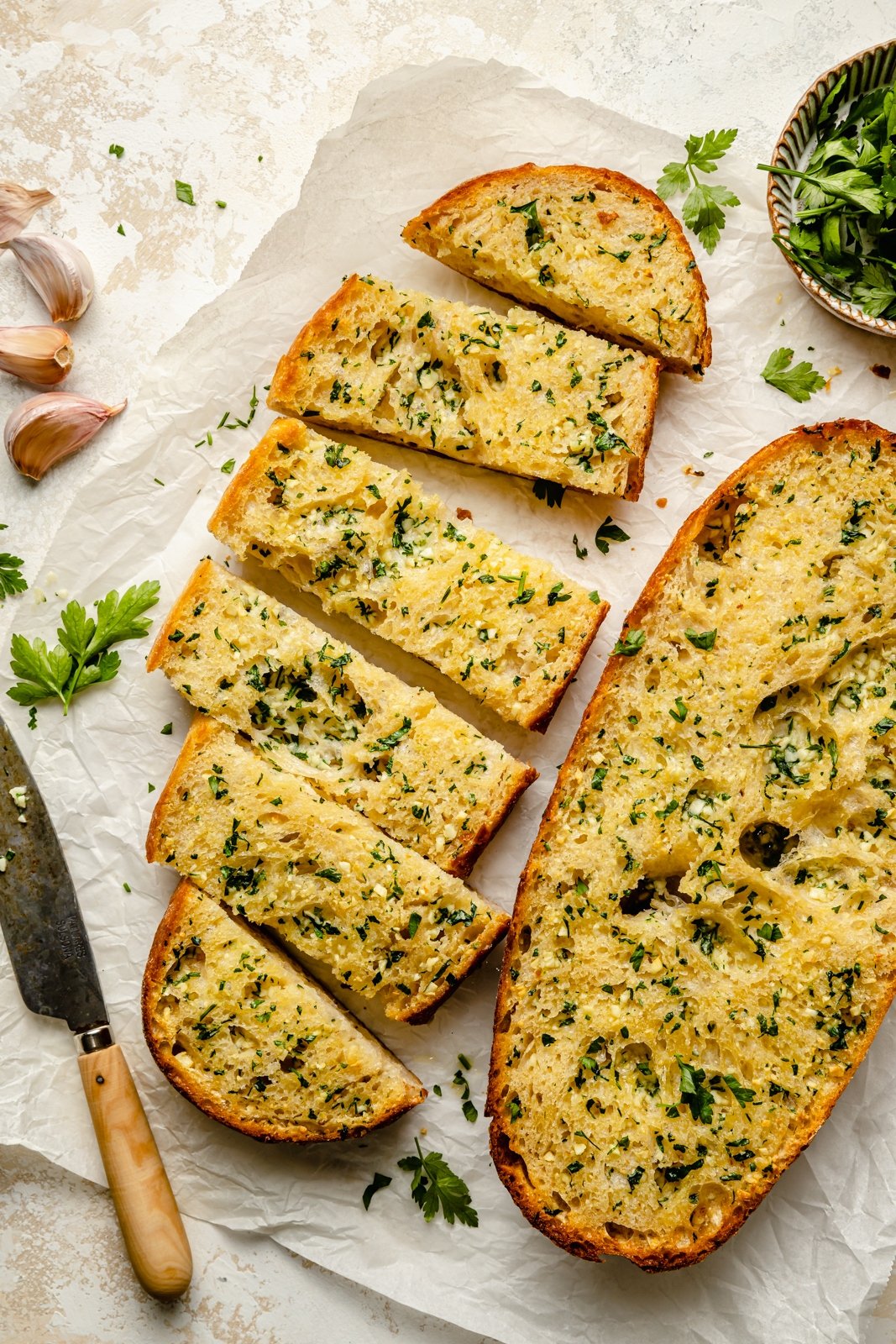 homemade garlic bread sliced on parchment paper