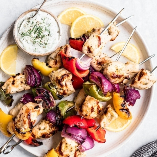 greek chicken kabobs on a plate with tzatziki sauce