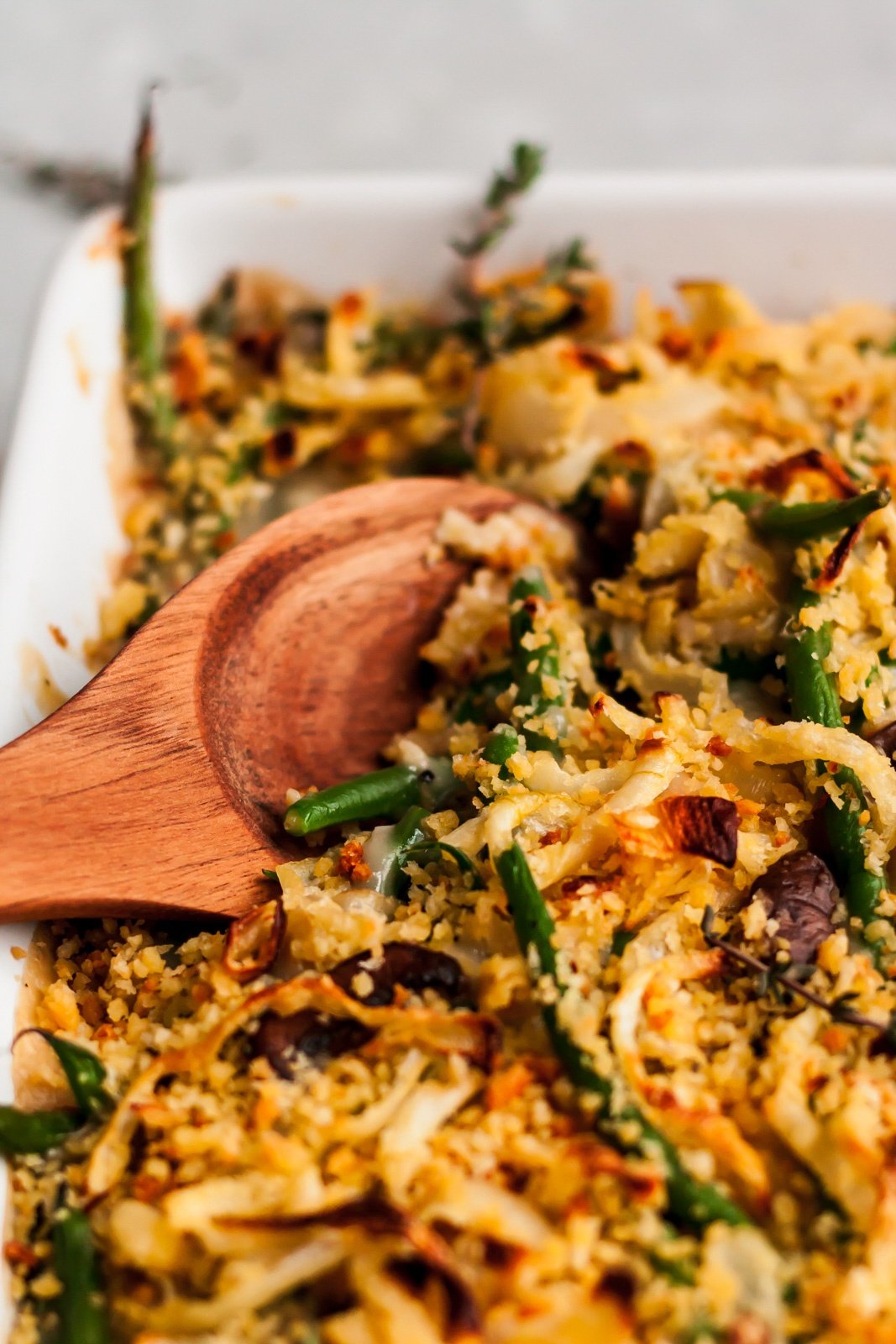 healthy green bean casserole in a baking dish with a wooden spoon