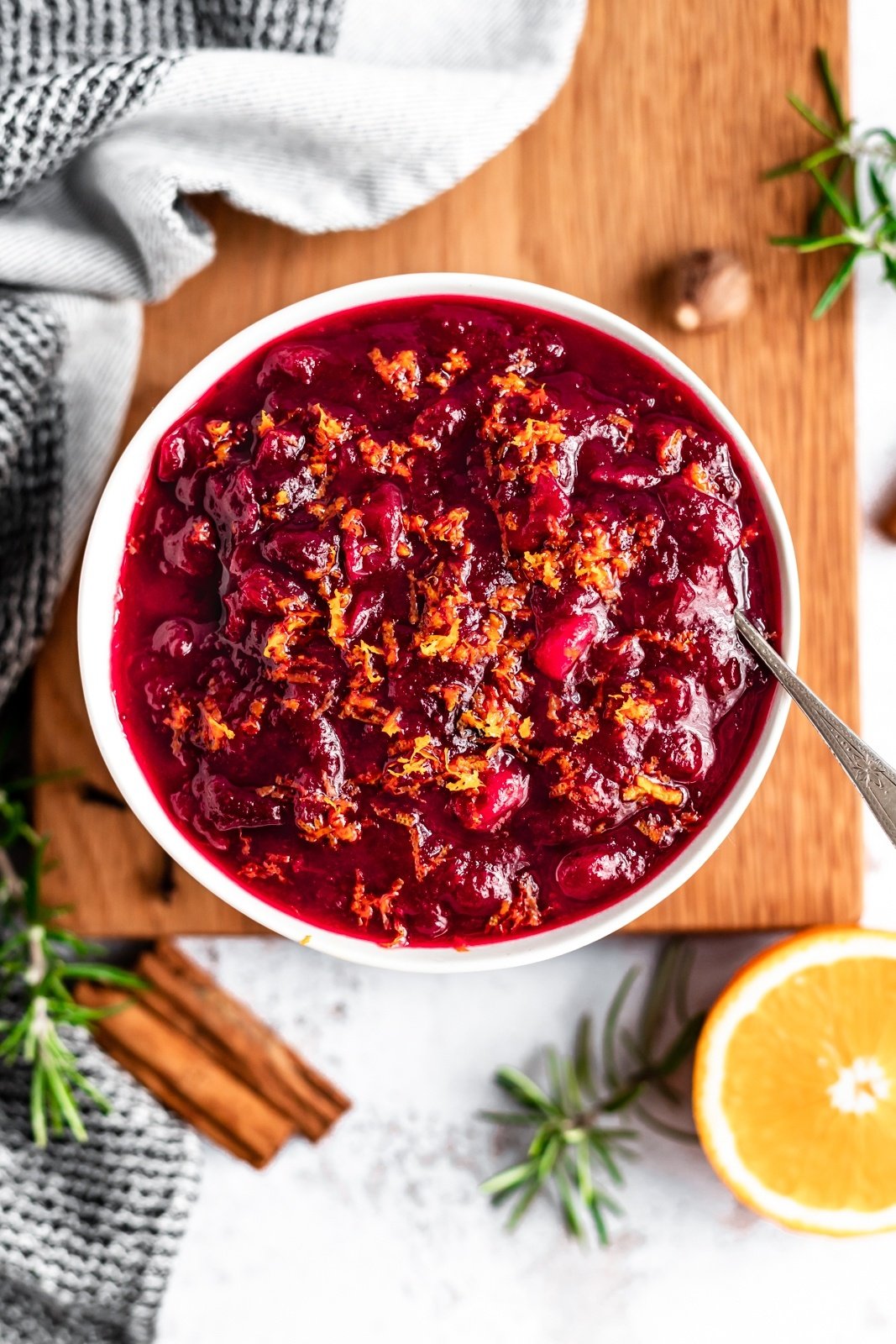 healthy orange cranberry sauce in a bowl on a board with a spoon