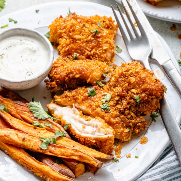 cornflake chicken with hot honey on a plate with french fries