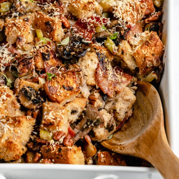 sourdough mushroom stuffing in a baking dish with a wooden spoon