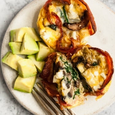 bacon egg cups with avocado cubes on a plate with a fork