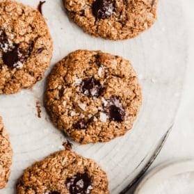 healthy oatmeal chocolate chip cookies on a cooling rack with sea salt on the side