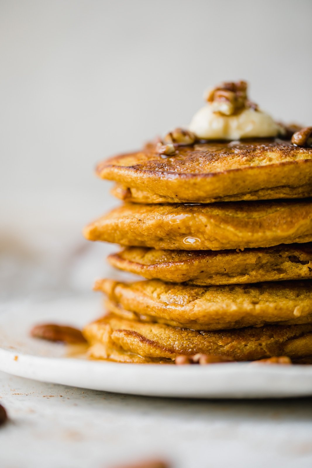 stack of healthy pumpkin pancakes on a plate with maple syrup