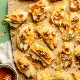 parmesan pear crostini with walnuts and honey on a cutting board