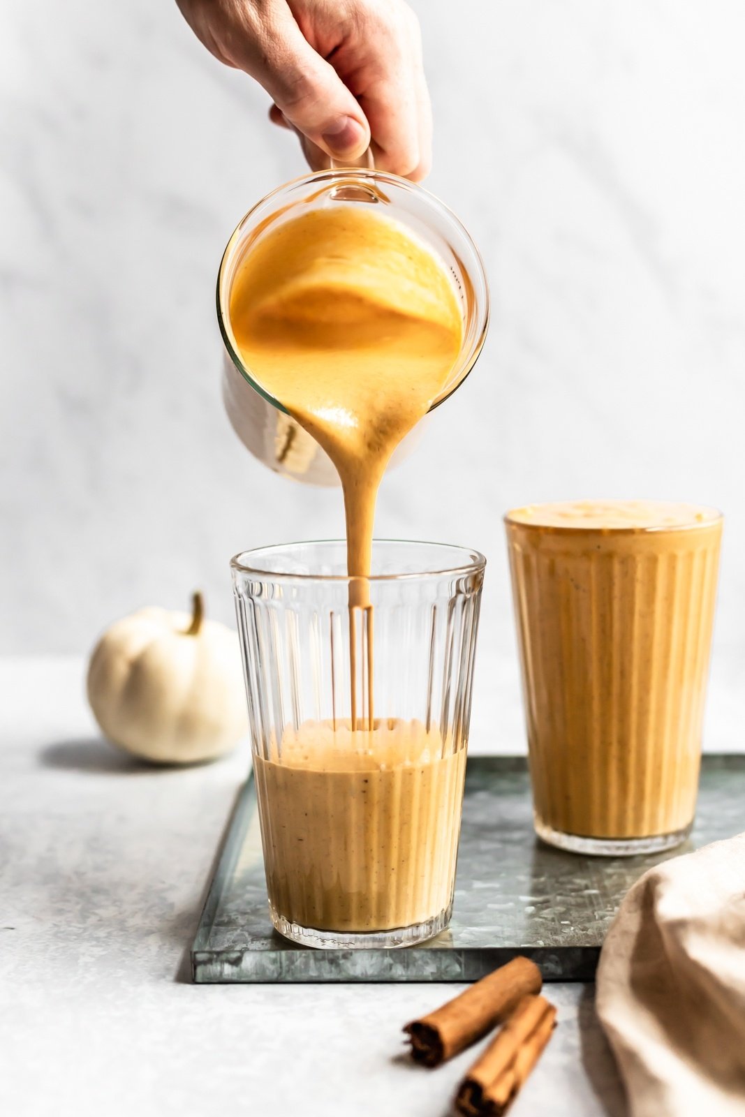 healthy pumpkin smoothie being poured into glasses