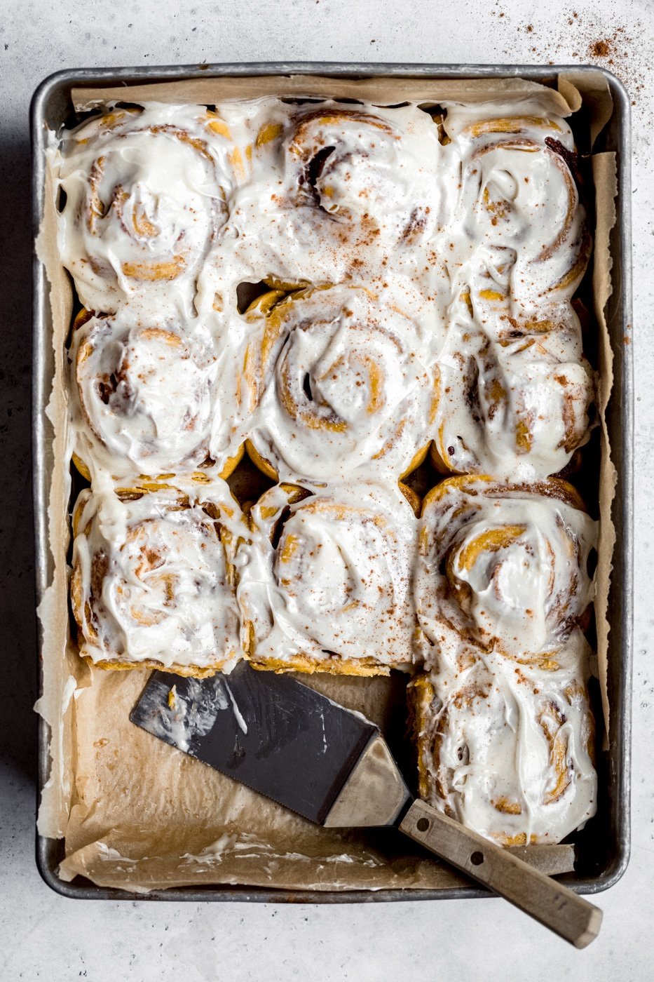 pumpkin cinnamon rolls in a pan with a spatula