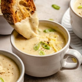 dipping bread into roasted cauliflower soup