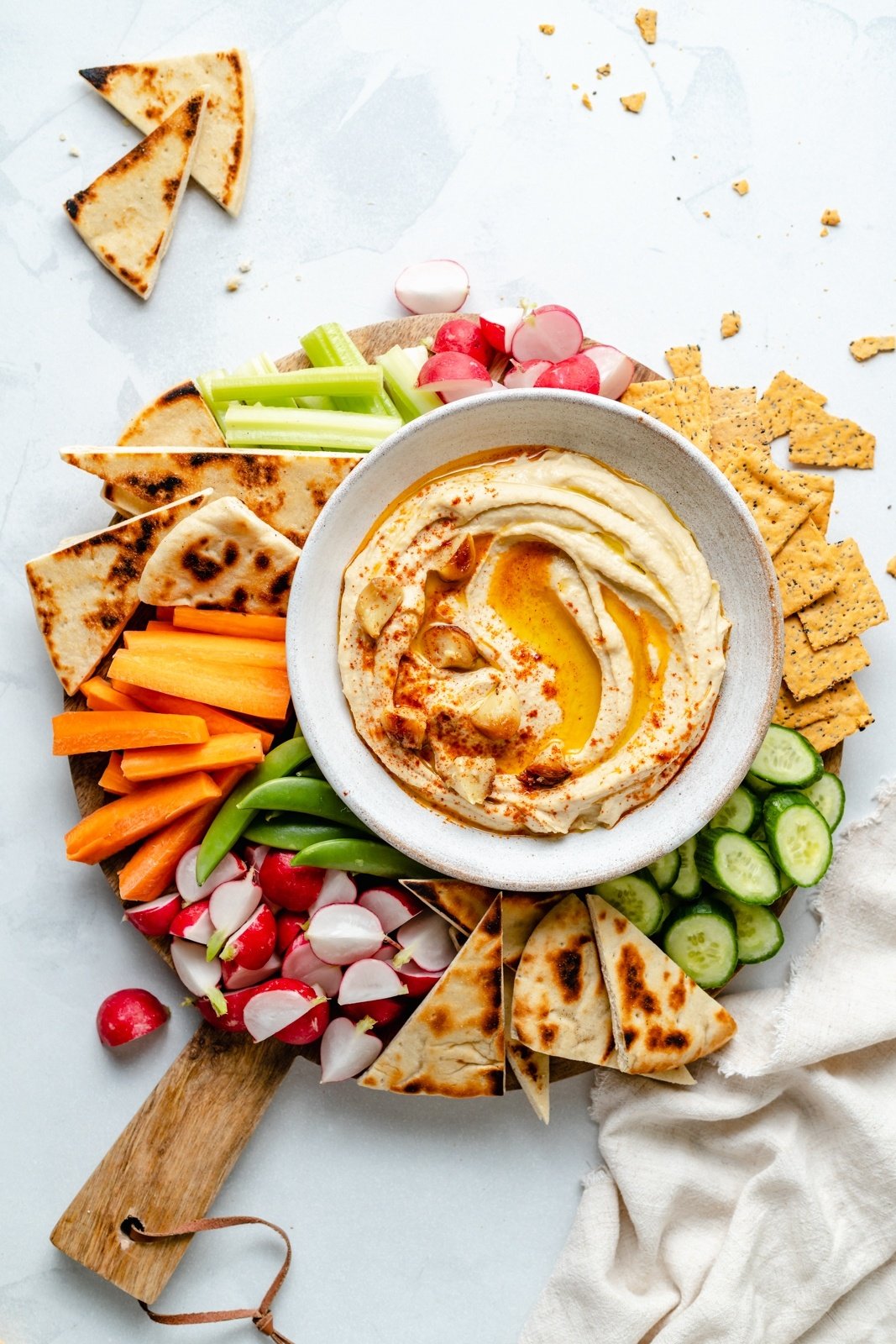 roasted garlic hummus in a bowl surrounded by veggies and pita bread