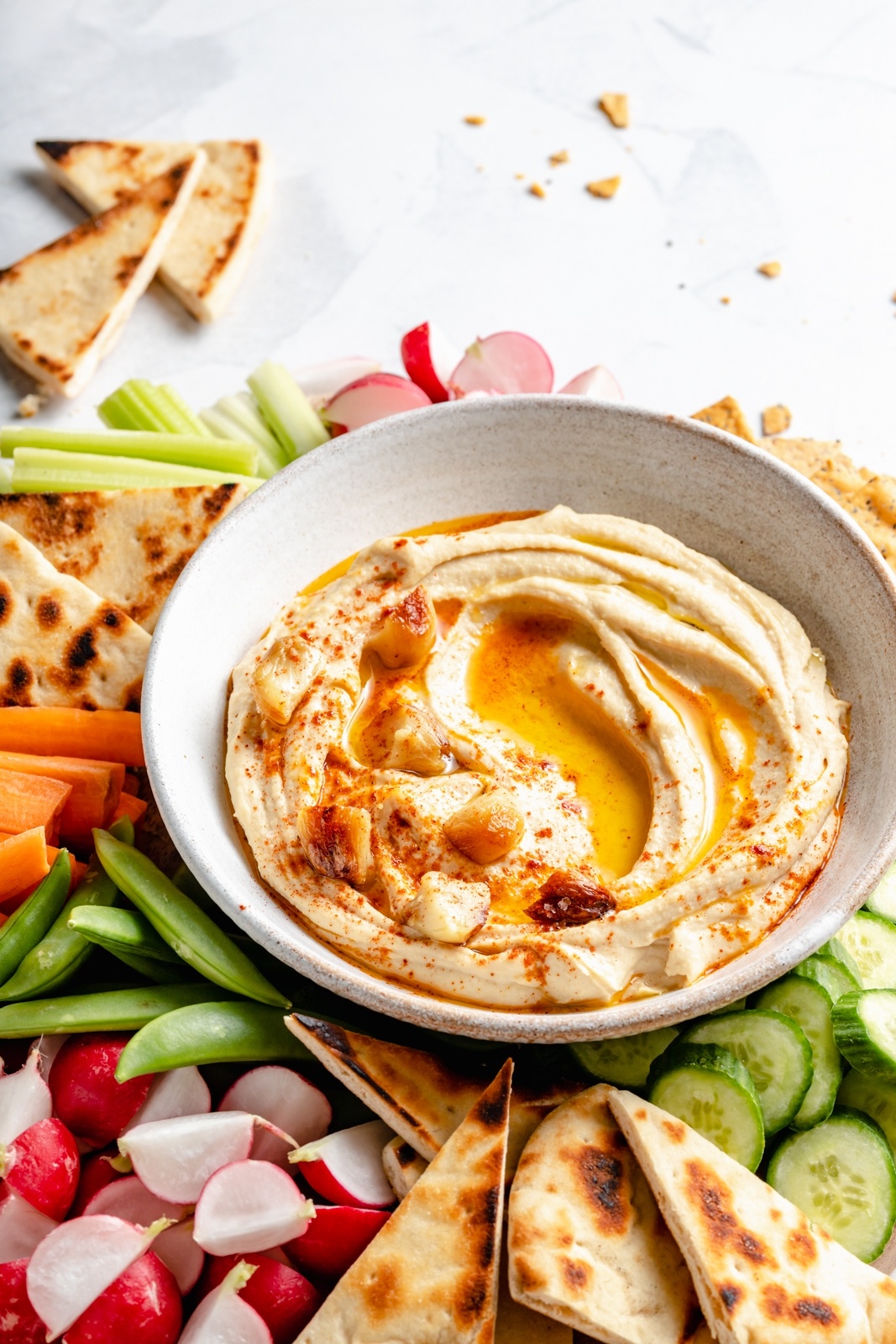 roasted garlic hummus in a bowl surrounded by veggies