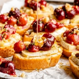 drizzling honey on a roasted grape and brie crostini