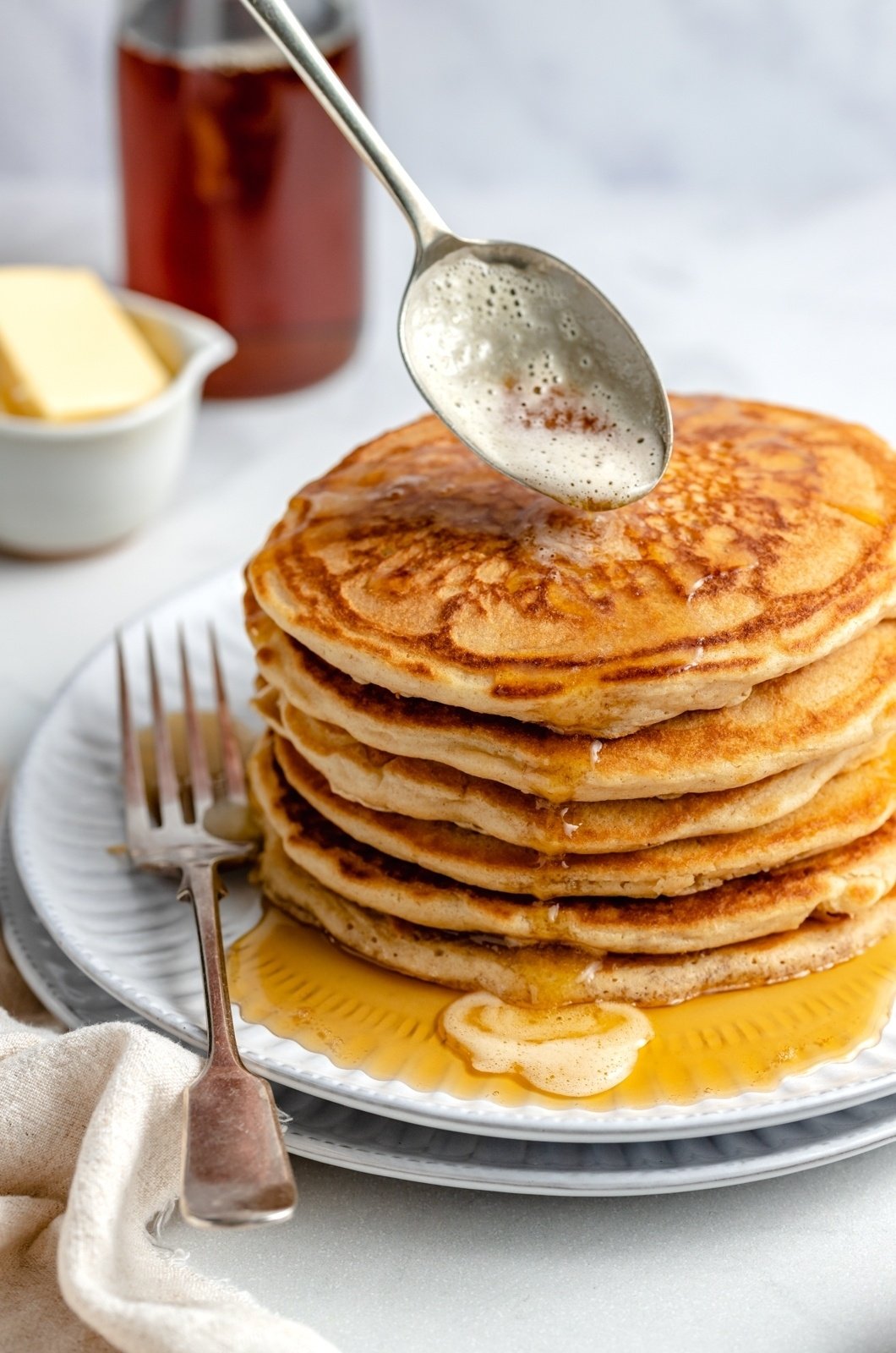 spooning brown butter onto a stack of brown butter pancakes