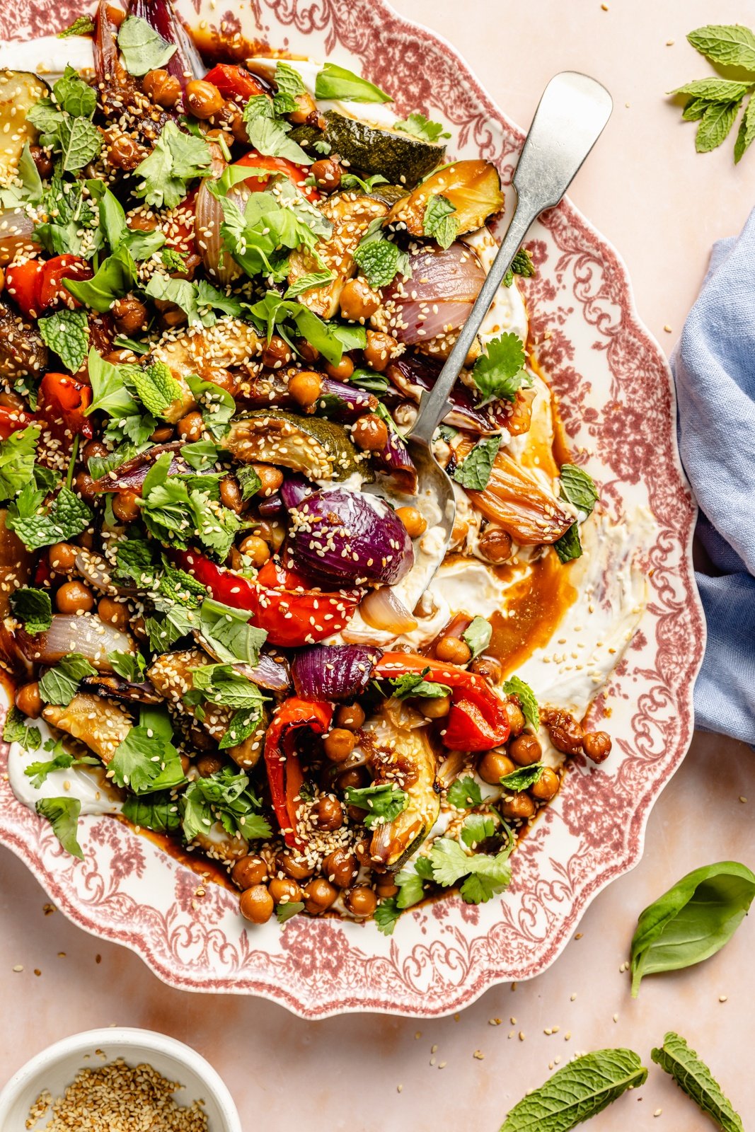 sesame roasted vegetables and chickpeas on a platter with tahini garlic yogurt sauce