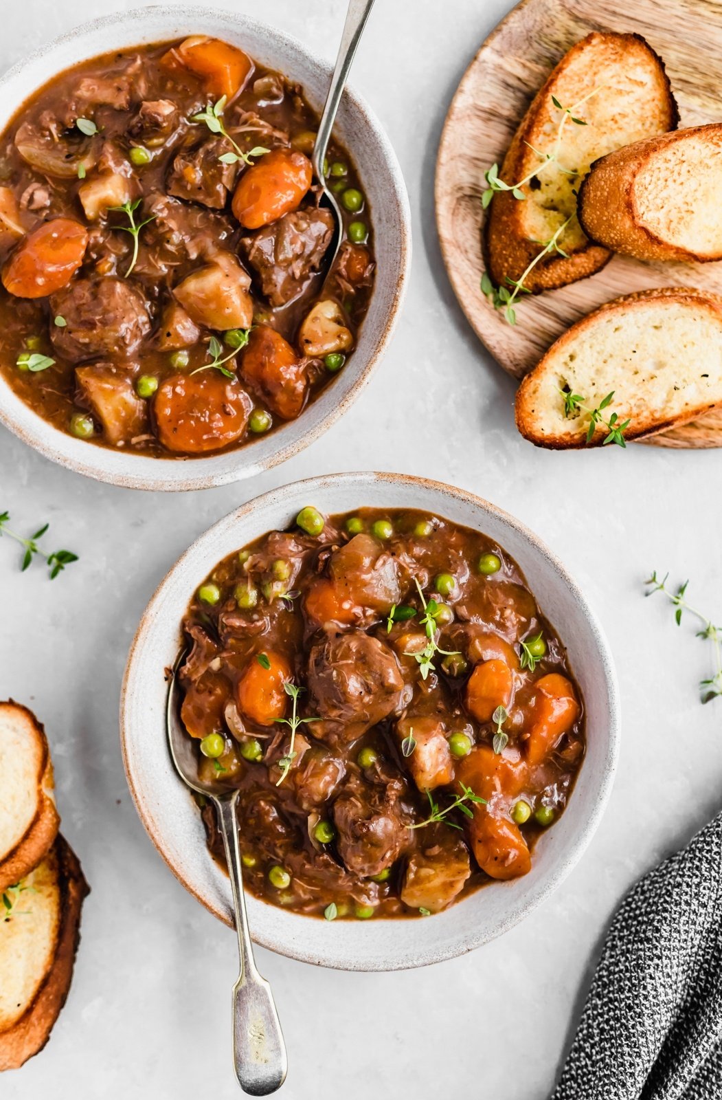 slow cooker beef stew in two bowls with spoons and bread on the side