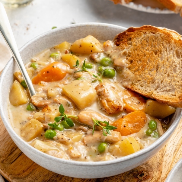 slow cooker white wine chicken stew in a bowl with a piece of bread