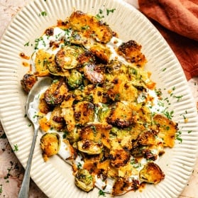 spicy roasted brussels sprouts on a platter with tahini yogurt sauce