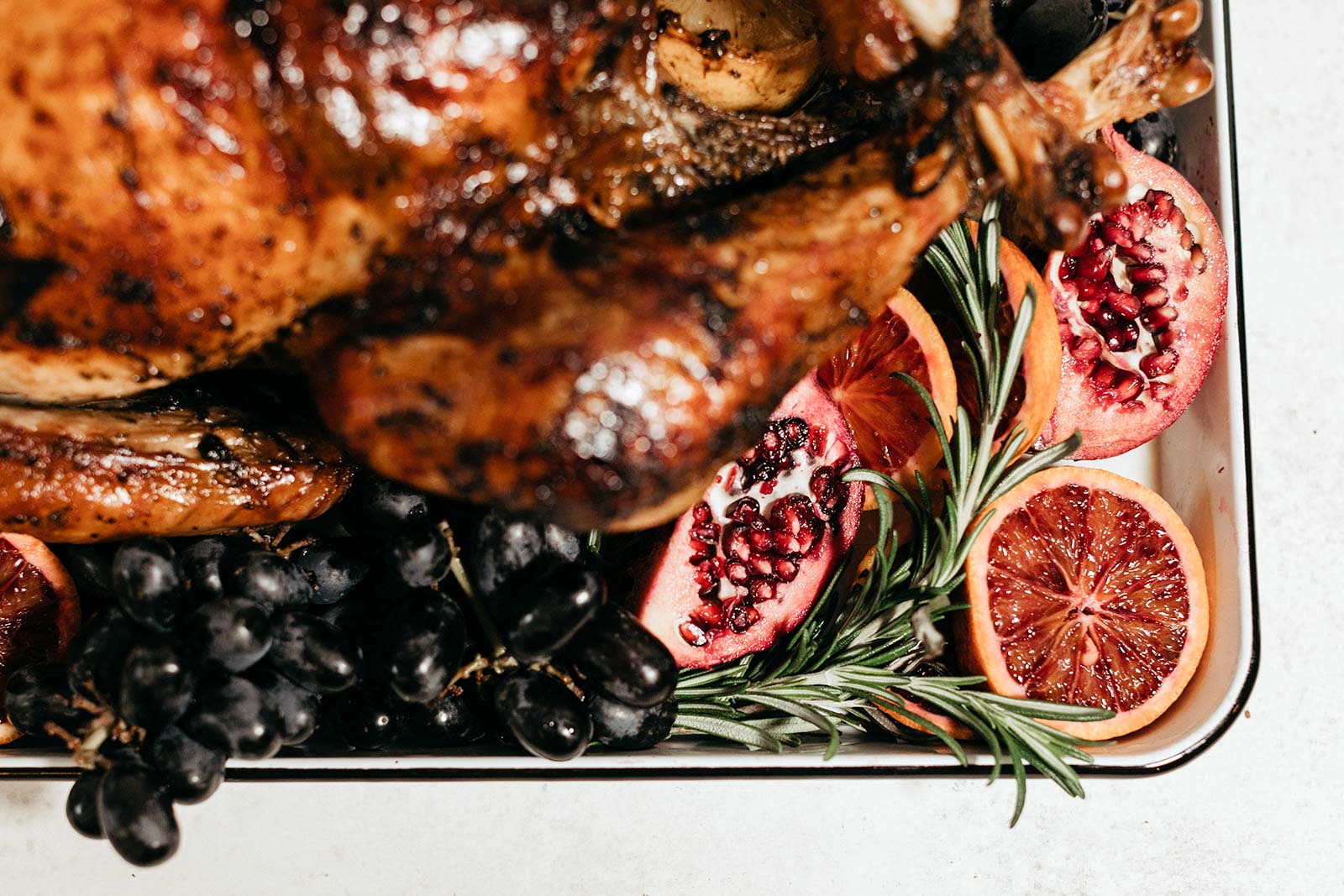 whole thanksgiving turkey on a platter with grapes and pomegranate