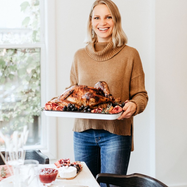 blonde woman holding a turkey on a platter