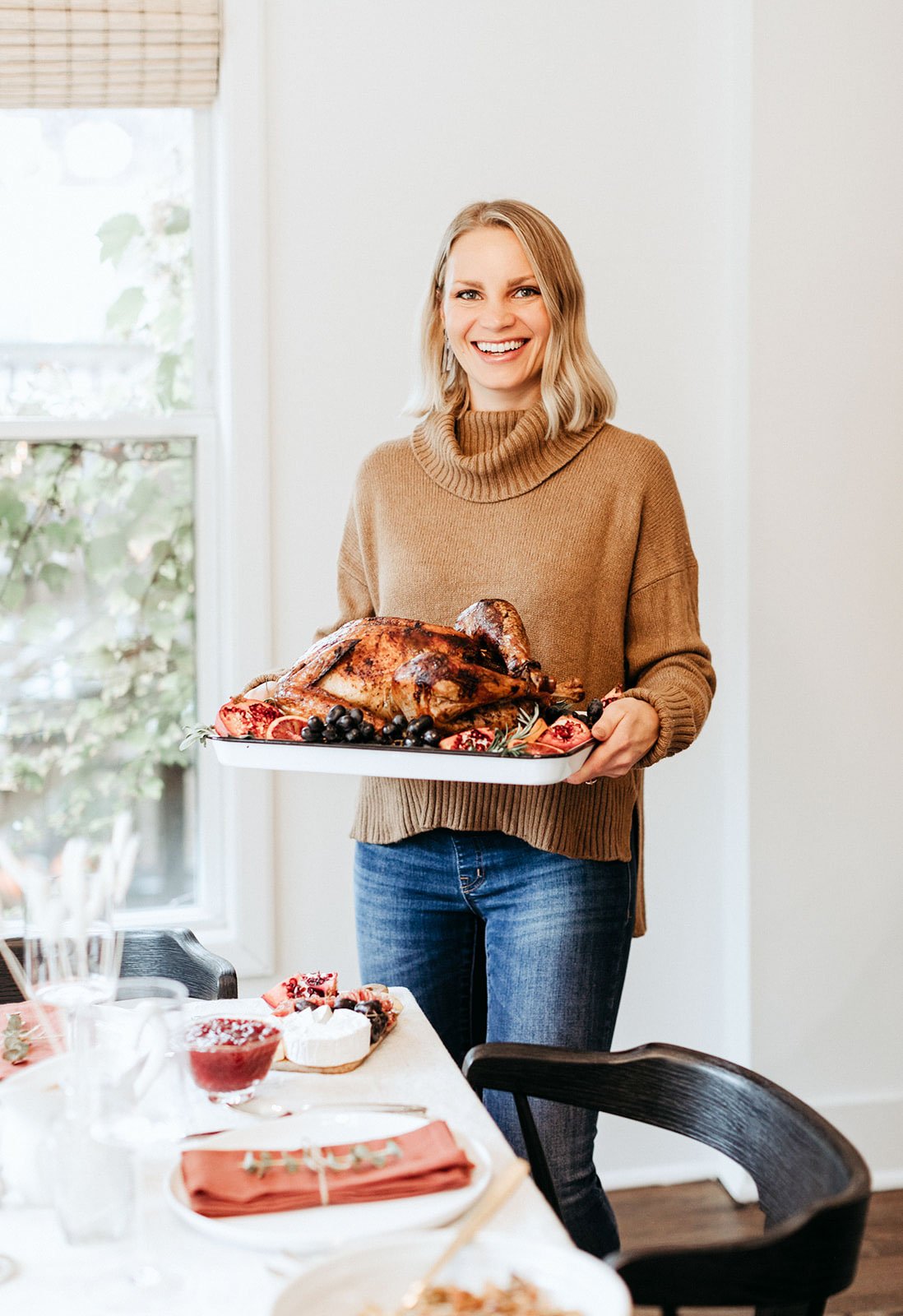 blonde woman holding a platter with a thanksgiving turkey