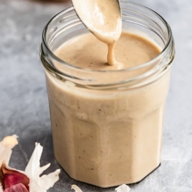 spooning basic tahini sauce out of a jar