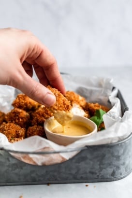 dipping a crispy baked chicken nugget in honey mustard