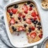 berry baked oatmeal in a baking dish with a slice cut out