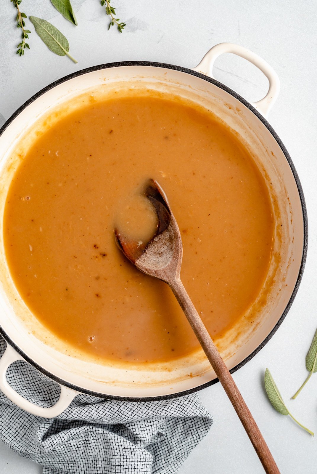 homemade turkey gravy in a pot with a wooden spoon