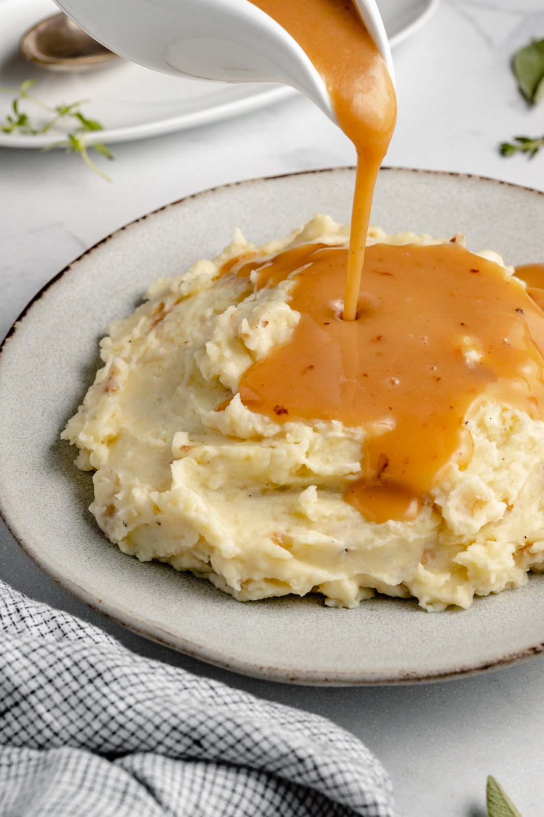 pouring turkey gravy onto a plate of mashed potatoes