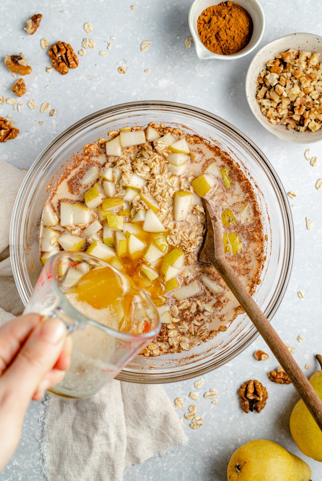 adding brown butter to a bowl with pear oatmeal bake ingredients