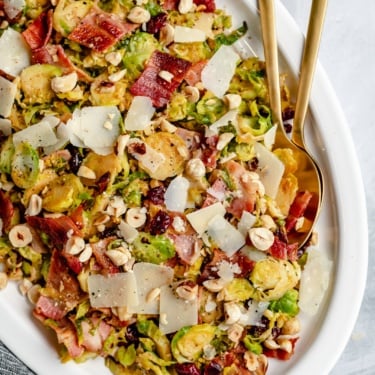 warm brussels sprouts salad with bacon on a platter with serving utensils