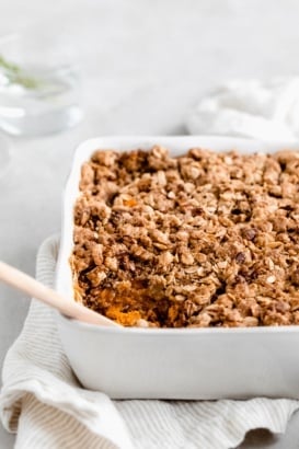 healthy sweet potato casserole in a baking dish with a wooden spoon